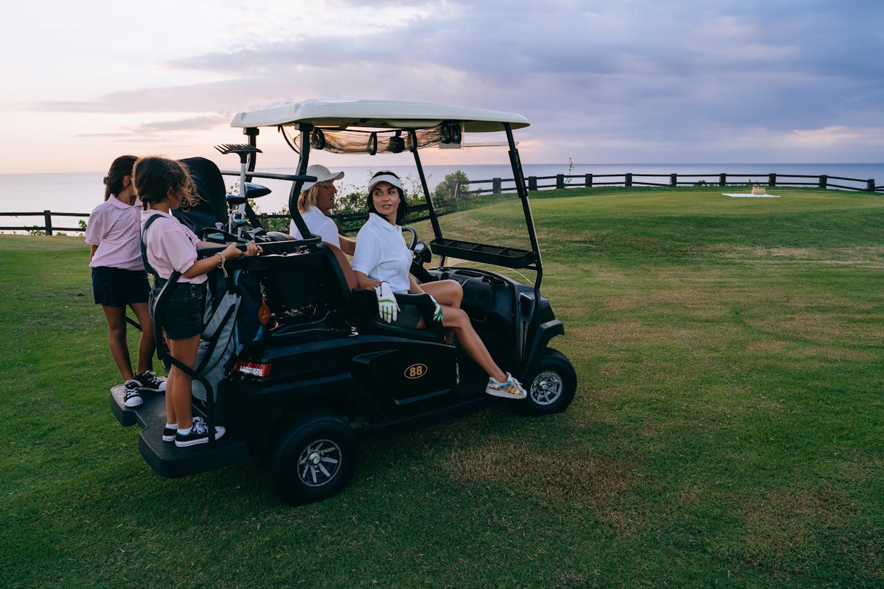 creative-03 Family and friends ride a golf cart during a leisure golf outing at sunset by the ocean.